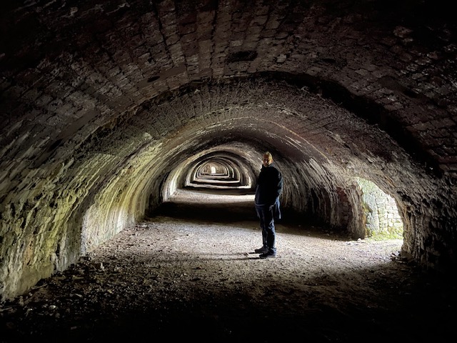 Author photo in mossy brick catacombs.